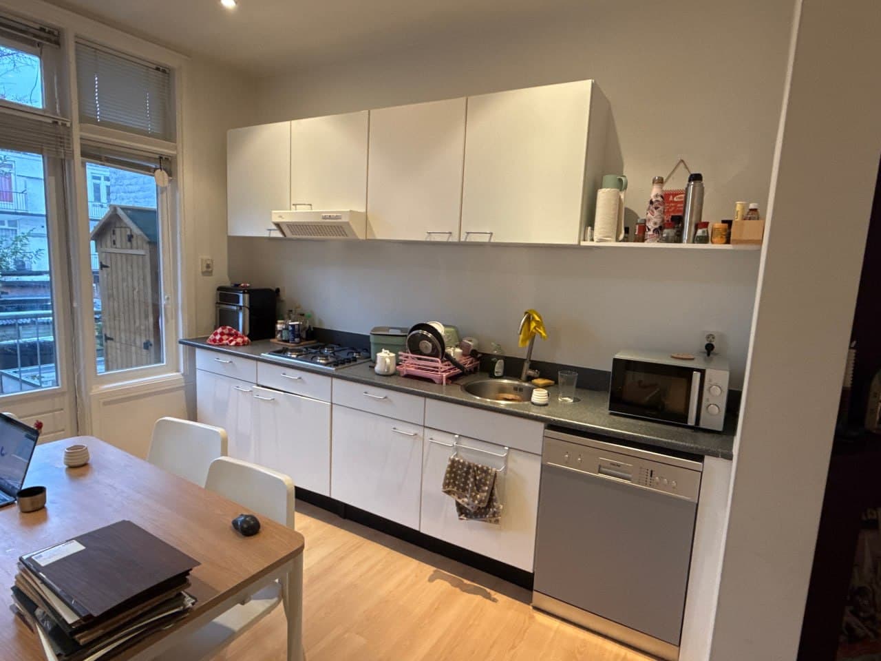 Witte keuken met eiland naar saliegroene greeploze keuken (voor)
